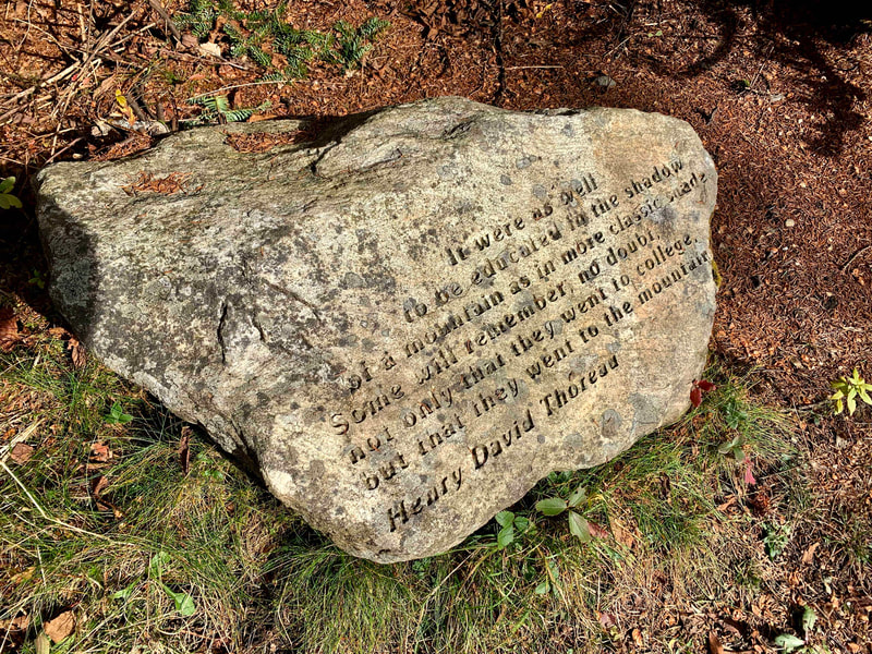 Small boulder with inscription: It were as well to be educated in the shadow of a mountain as in more classic shade. Some will remember, no doubt, not only that they went to college, but that they went to the mountains. Henry David Thoreau.