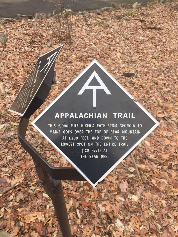 Brown and white Appalachian Trail sign reading: This 2,000 mile hiker’s path from Georgia to Maine goes over the top of Bear Mountain at 1,300 feet, and down to the lowest spot on the entire trail (120 feet) at the Bear End.